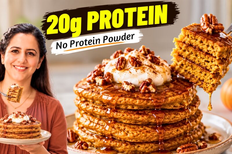 Stack of fluffy pumpkin protein pancakes topped with Greek yogurt and pecans, drizzled with maple syrup
