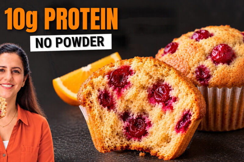 Cranberry orange muffin split open showing a soft crumb with whole cranberries, next to a domed muffin and an orange wedge.