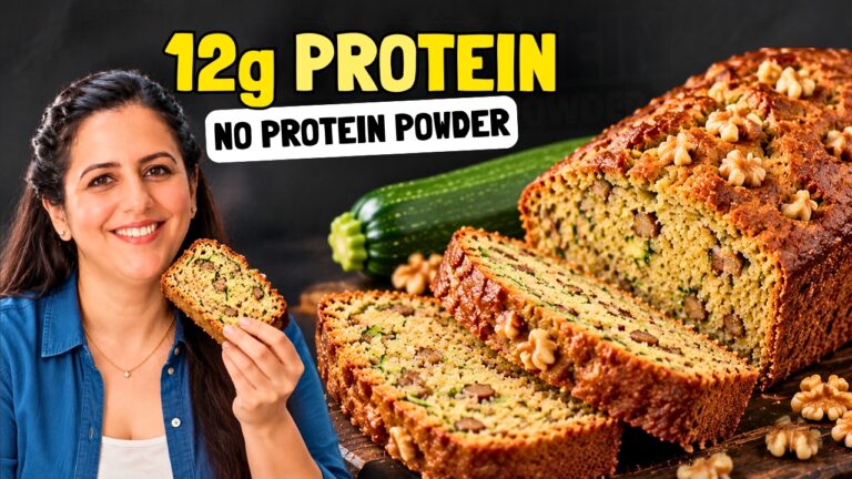 Sliced high protein zucchini bread with walnuts on a wooden board, with a whole zucchini beside it