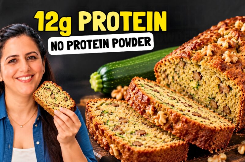 Sliced high protein zucchini bread with walnuts on a wooden board, with a whole zucchini beside it