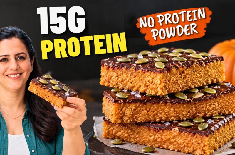 Stack of three no-bake pumpkin protein bars with a dark chocolate top and pumpkin seeds •